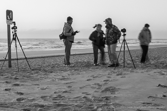 Ken Arni shares information with Bill Sargent; two Coastal Camera Club members pass by
